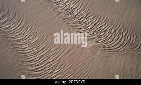 A close view of ripples on water surface created by strong wind in sand on a beach Stock Photo