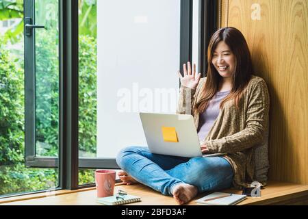 Asian business woman using technology laptop and working from home with say hello or bye, freelance and entrepreneur, creative design and blogger, soc Stock Photo