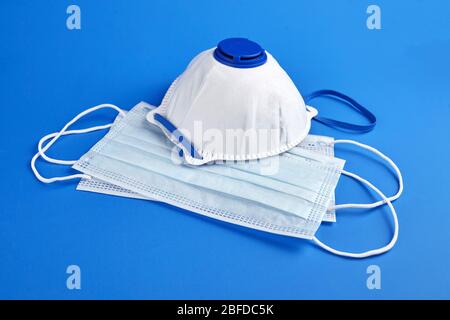 Respirator FFP2 and surgical masks on blue background. Anti dust breathable disposable earloop mouth face masks provide protection against the spread Stock Photo