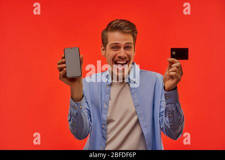 Happy man holding a phone and a credit card. Stock Photo