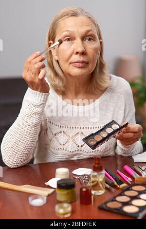 beautiful senior woman after applying make up holding a brush Stock Photo