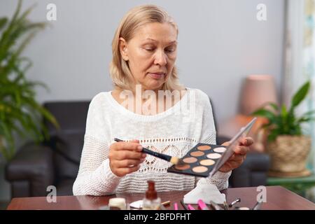 beautiful senior woman after applying make up holding a brush Stock Photo
