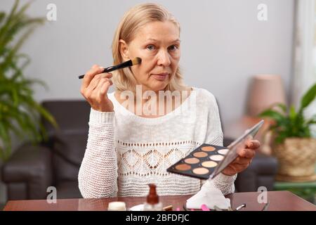 beautiful senior woman after applying make up holding a brush Stock Photo