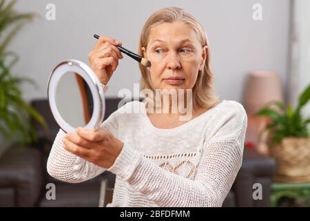 beautiful senior woman after applying make up holding a brush Stock Photo