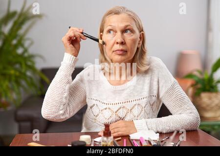 beautiful senior woman after applying make up holding a brush Stock Photo