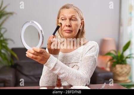 beautiful senior woman after applying make up holding a brush Stock Photo