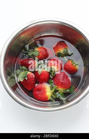 Soaking fresh strawberries in stainless steel bowl isolated on white background