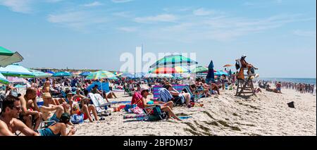 Babylon, New York, USA - 14 July 2019: Lifeguard stand looking over the water with a crowded beach of people behind it all looking at the ocean. Stock Photo