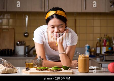 Woman having avocado peanut butter toast for a healthy breakfast at home Stock Photo