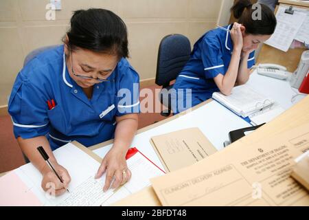 Two hospital nurses in dark blue uniforms filing patient notes in a London hospital. Stock Photo