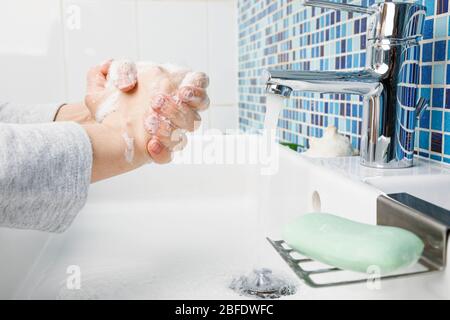 Child diligently washing hands with antibacterial soap and water performing basic protective measures against spreading of coronavirus COVID-19 deseas Stock Photo