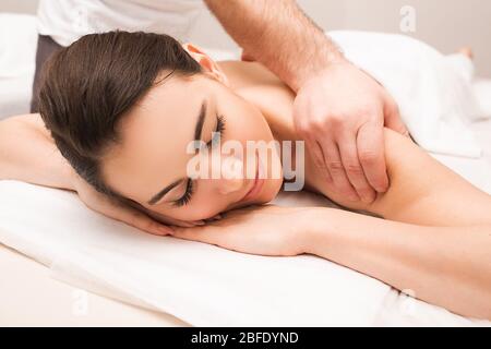 A woman receives a massage of the cervical vertebrae series. Massage relaxes the muscles of the neck and back. Stock Photo