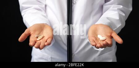 Cropped view of female Doctor holding in hands Pills to choose. Difficult Choice between drugs. Placebo drugs concept. Healthcare concept. Stock Photo