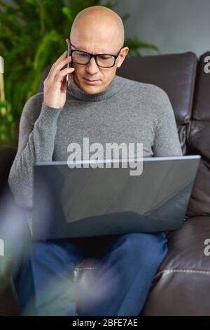 Man working on a blank laptop on a comfortable sofa at home Stock Photo