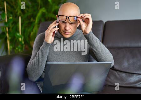 Man working on a blank laptop on a comfortable sofa at home Stock Photo