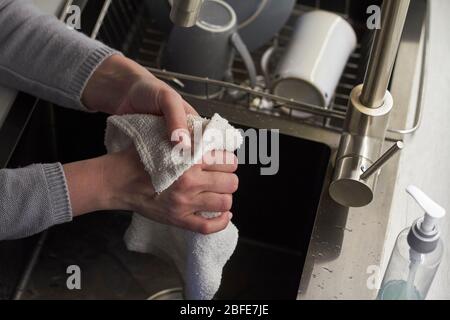 Hygiene concept, top view woman washes hands in the kitchen sink and wipes her hands with towel, selective focus