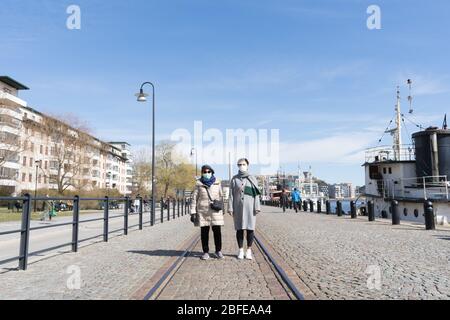 Stockholm, Sweden coronavirus emergency. Family mom and daughter are walking in the street wearing protection safety mask Stock Photo