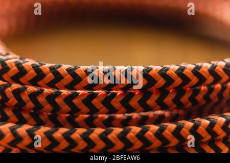 A close up of an orange and black braided cable interwided and wrapped in a circle Stock Photo