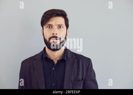 Puzzled insecure man in casual jacket on a gray background. Expression of emotion Stock Photo