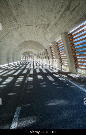 tunnel in the alps built of concrete with one side shut with wooden planks creating beautiful light stripes on the ground Stock Photo