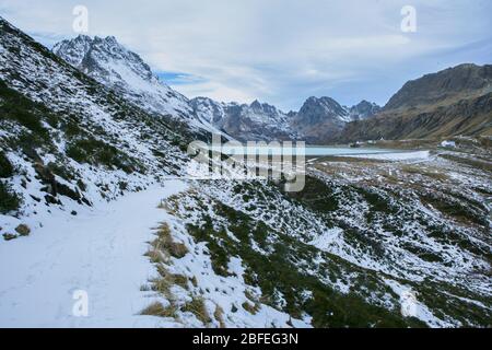 small hiking trail in the mountains with snow on the silvretta mountains with a view of the dam Stock Photo