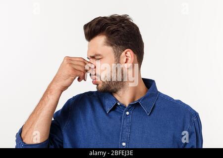 Man holding his nose against a bad smell isolated over grey background. Stock Photo