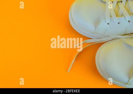 Pair of white shoes on yellow background. Trendy summer color Stock Photo