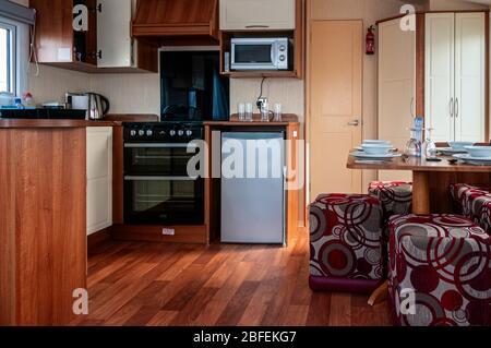 The attractive use of wood panelling and furnishings to provide a light, airy, dining and kitchen area with plenty of cupboard space inside a caravan Stock Photo