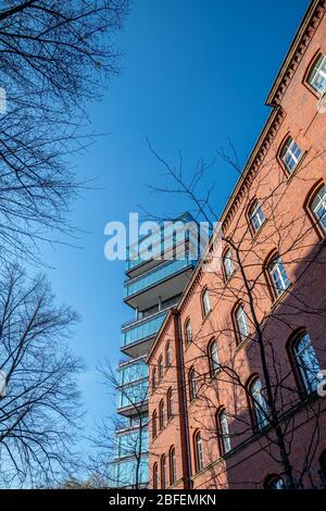 Old red brick building in front of architectural modern office building and a blue sky Stock Photo