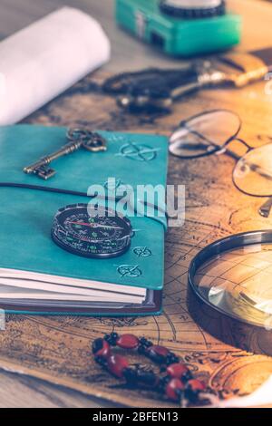 Travel notebook lying on an old map with old glasses, a flashlight, expedition accessories, Retro style. Expedition planning concept Stock Photo