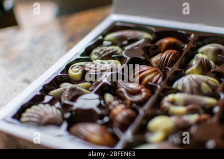 Seashell chocolates in a white box on a kitchen worktop. White and dark chocolates Stock Photo