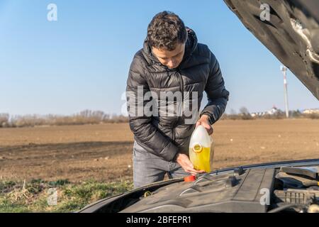 man pours into the car yellow liquid for the wiper Stock Photo