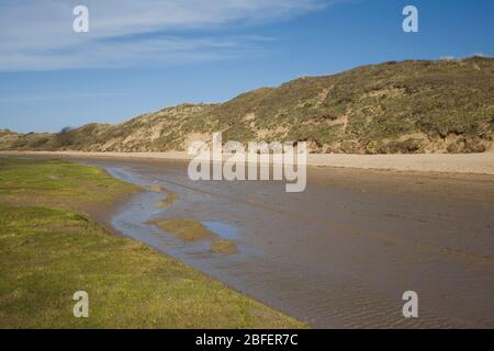 edge of Ogmore river in Merthyr Mawr nature reserve with grass and damp sand Stock Photo