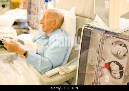 A kidney patient on his regular visit to the renal dialysis ward of a London hospital where he is  connected to a hemodialysis machine which essential Stock Photo