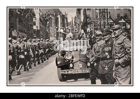 Vintage Nuremberg Rally 1935, Germany - SA Sturmabteilung political militia troops of the Nazi party, march past Adolf Hitler during a parade in the city. 1930’s Adolf Hitler wearing swastika armband in military parade, standing in Mercedes open car with Heil Hitler salute to passing marching Sturmabteilung troops Hermann Goring in foreground Nuremberg Germany