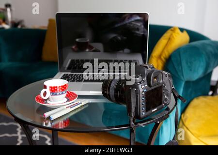 Coffee, laptop and camera with sofa in the background Stock Photo