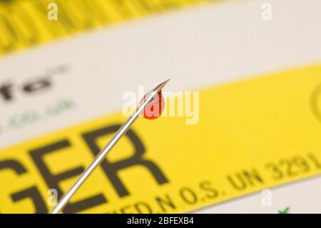 A droplet of blood seen on the end of needle as ready to be disposed of in a yellow container for 'sharps'.  (Medicimage)(Model Released) Stock Photo
