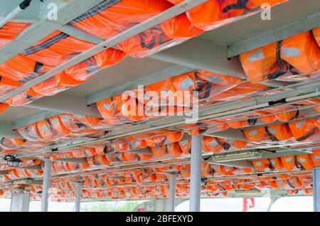 Orange life jackets or vest on in overhead racks ready for use on transportation boat. Safety equipment on a pleasure boat. Stock Photo