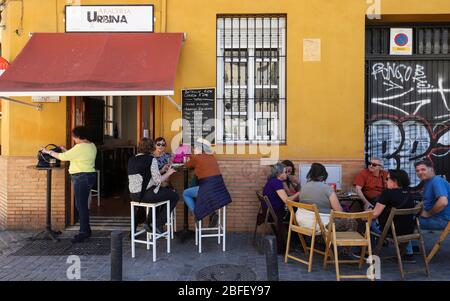 Tourists enjoy at traditional grocery store Urbina terrace typically Spanish cuisine. It located near Macarena square in Seville. Stock Photo