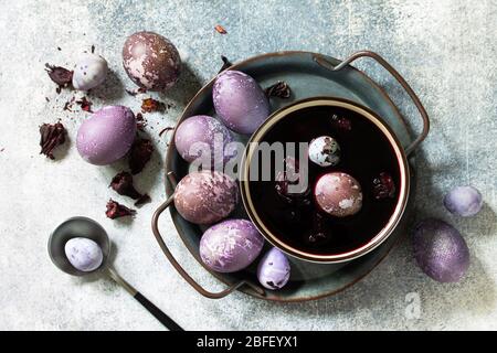Natural egg dye purple. Easter eggs are painted with natural egg dye from Hibiscus tea on a gray stone countertop. Top view flat lay background. Stock Photo
