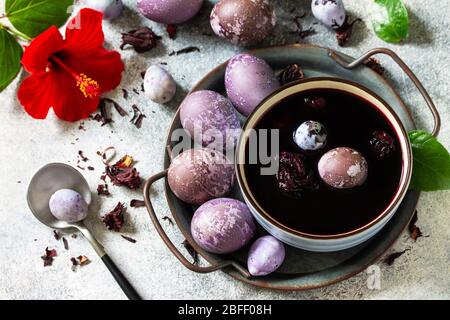 Natural egg dye purple. Easter eggs are painted with natural egg dye from Hibiscus tea on a gray stone countertop. Stock Photo