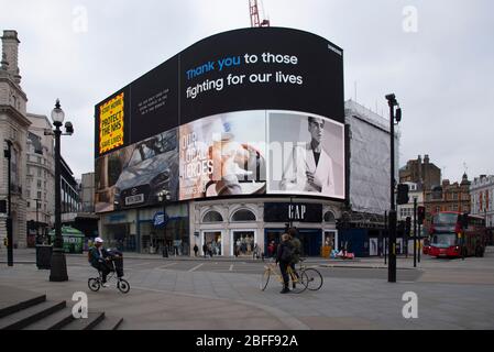 London, UK. 18th Apr, 2020. Cyclists look at messages of support to frontline NHS workers on the digital billboard in Piccadilly Circus, London, UK on April 18, 2020. (Photo by Claire Doherty/Sipa USA) Credit: Sipa USA/Alamy Live News Stock Photo