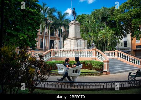 Lovers couple in The Parque Hidalgo and statue of Manuel Cepeda Peraza, Merida, Yucatan, Mexico Stock Photo