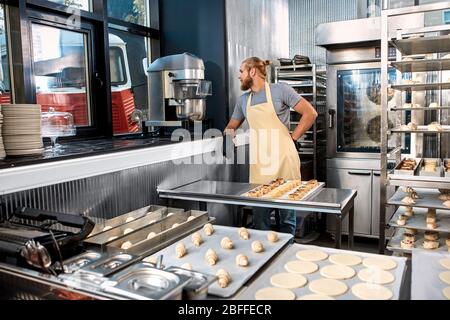 Young adult man working in modern bakery factory Stock Photo