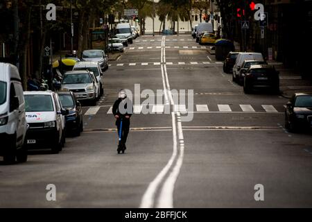 A man goes on an electric scooter by an empty  street of Barcelona's La Barceloneta maritime district.  The state of alarm decreed to face the coronavirus spread  has caused a 70 percent drop on the use of private vehicles. Stock Photo