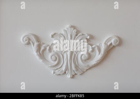 Expensive interior. Stucco elements on light luxury wall. White patterned. Mouldings element from gypsum. Roccoco style. gypsum interior element on th Stock Photo