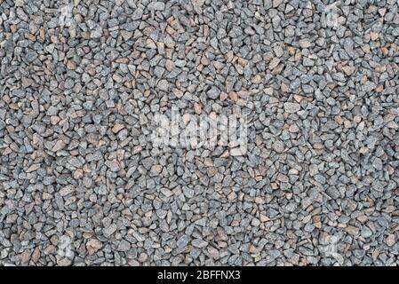 Crushed rock is scattered on the ground, surface. Close-up of crushed f gray granite, gravel for construction. Background, texture. Stock Photo