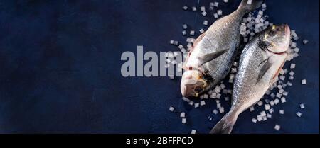 Two raw dorado fishes on wooden dark blue background Stock Photo
