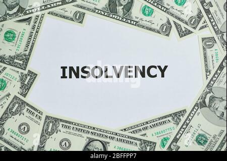 word insolvency printed on a white paper, around are lying Dollar bills Stock Photo