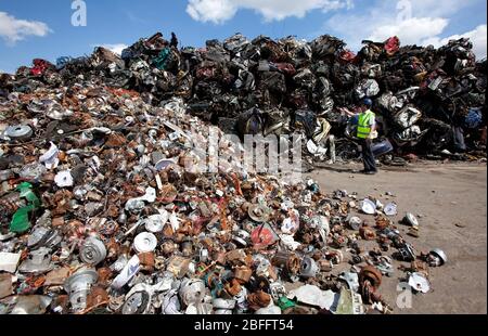 A scrapyard worker stands next to a pile of compacted cars Stock Photo ...
